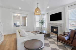 Living room with a high end fireplace, light hardwood / wood-style flooring, and crown molding