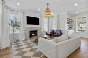 Living room with light hardwood / wood-style floors, a high end fireplace, and ornamental molding