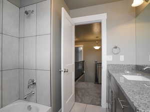 Bathroom with washtub / shower combination, tile patterned floors, and vanity