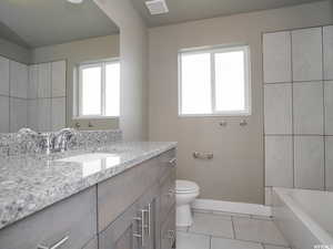 Bathroom with tile patterned floors, vanity, a bathing tub, and toilet