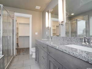 Bathroom featuring vanity, toilet, a shower with door, and tile patterned flooring