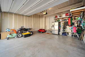 Garage featuring stainless steel fridge with ice dispenser and a garage door opener