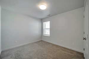 Empty room featuring a textured ceiling and carpet flooring