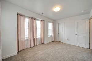 Unfurnished bedroom featuring multiple windows and light carpet