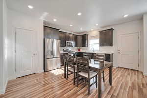 Kitchen featuring dark brown cabinets, sink, light hardwood / wood-style flooring, backsplash, and stainless steel appliances