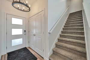 Foyer with light wood-type flooring and an inviting chandelier