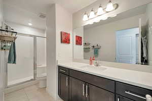 Bathroom featuring toilet, tile patterned floors, vanity, and an enclosed shower