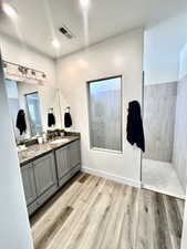 Bathroom with wood-type flooring, a tile shower, and vanity