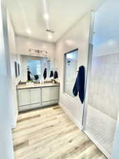 Bathroom featuring hardwood / wood-style flooring, walk in shower, and vanity