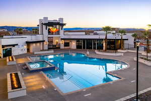 Pool at dusk featuring a community hot tub, a mountain view, and a patio area