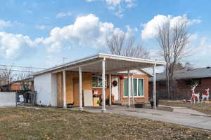 View of front facade featuring a front yard and a carport