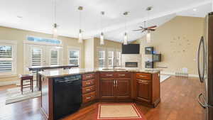 Kitchen with sink, stainless steel refrigerator, dishwasher, and an island with sink