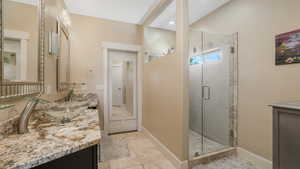 Bathroom featuring a shower with shower door, tile patterned floors, and vanity