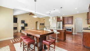 Dining space featuring dark wood-type flooring, vaulted ceiling, sink, and a fireplace