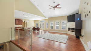 Living room featuring hardwood / wood-style floors, a fireplace, sink, high vaulted ceiling, and ceiling fan