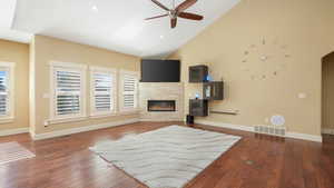 Living room featuring a fireplace, dark hardwood / wood-style floors, high vaulted ceiling, and ceiling fan