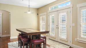 Dining area with dark wood-type flooring, a wealth of natural light, and french doors