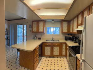 Kitchen featuring white fridge, sink, kitchen peninsula, electric range, and a breakfast bar area