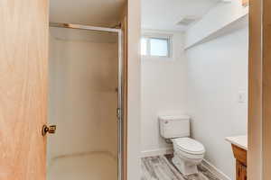 Bathroom with vanity, a shower with shower door, toilet, and hardwood / wood-style flooring