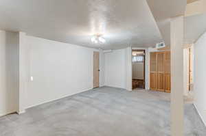 Basement featuring light colored carpet and a textured ceiling