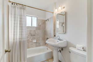 Bathroom with toilet and shower / bathtub combination with curtain