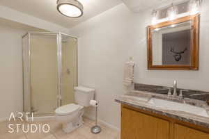 Bathroom with toilet, an enclosed shower, tile patterned floors, and vanity