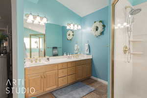 Bathroom featuring vanity, a shower with shower door, and lofted ceiling