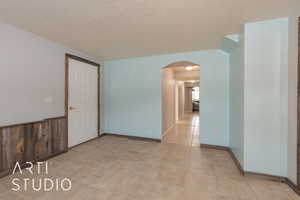 Unfurnished room with a textured ceiling and wooden walls