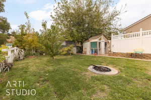 View of yard with an outdoor fire pit and a storage shed