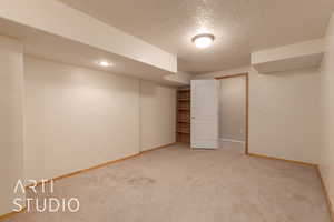 Basement with a textured ceiling and carpet floors