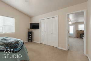 Bedroom featuring light carpet, a textured ceiling, vaulted ceiling, and ceiling fan