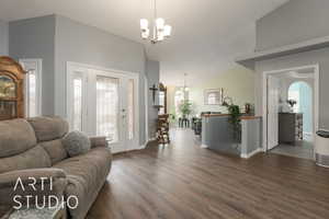 Living room featuring dark wood-type flooring, a chandelier, and vaulted ceiling