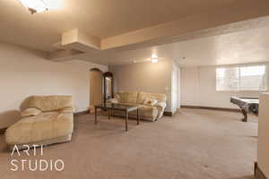 Living room featuring pool table, a textured ceiling, and carpet