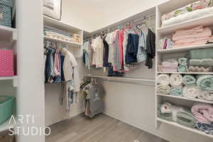 Spacious closet with light hardwood / wood-style floors and lofted ceiling