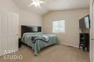 Bedroom featuring light colored carpet, vaulted ceiling, and ceiling fan