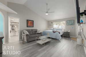 Bedroom featuring light hardwood / wood-style flooring, ceiling fan, a walk in closet, a closet, and lofted ceiling