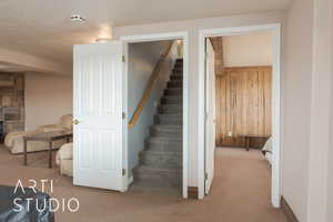 Stairway featuring a textured ceiling, wood walls, and carpet floors