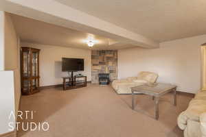 Carpeted living room with a textured ceiling, beam ceiling, and a wood stove