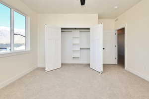 Unfurnished bedroom featuring a closet, ceiling fan, and light colored carpet