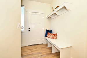 Mudroom with light wood-type flooring  and back door to townhouse.