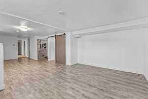 Interior space with an AC wall unit, a textured ceiling, light hardwood / wood-style flooring, and a barn door