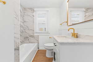 Bathroom with hardwood / wood-style flooring, a wealth of natural light, toilet, and vanity