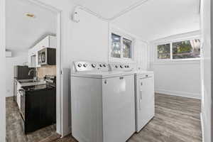 Laundry room with washing machine and clothes dryer and light hardwood / wood-style flooring