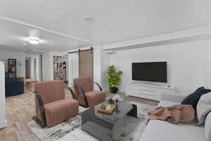 Living room with a barn door, light hardwood / wood-style flooring, and a textured ceiling