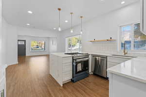 Kitchen with white cabinetry, light stone counters, light hardwood / wood-style flooring, and appliances with stainless steel finishes