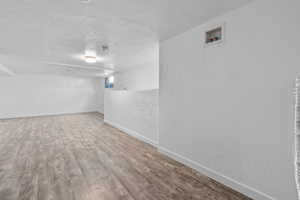 Basement with a textured ceiling and light hardwood / wood-style flooring