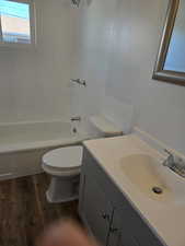 Full bathroom with vanity, wood-type flooring, shower / washtub combination, and toilet