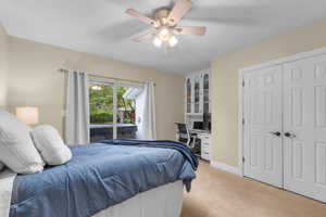 Bedroom featuring built in desk, light carpet, a closet, access to outside, and ceiling fan