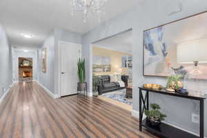 Hallway with hardwood / wood-style floors and a notable chandelier