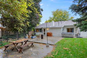 Back of property with a patio area, a hot tub, a yard, and central AC